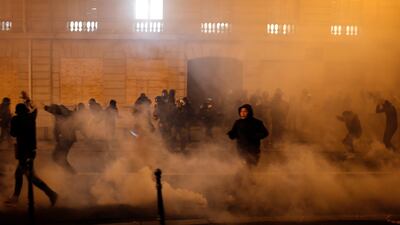 Demonstrators run away to avoid tear gas during clashes Saturday, Dec. 8, 2018 in Paris. AP