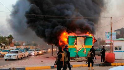 Security forces gather near a burning police checkpoint in Basra, southern Iraq. AP