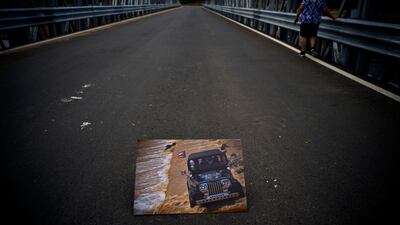 A printed photograph of a jeep crossing a river on October 7, 2017 sits placed on a new bridge that stands above the spot where the print was taken.