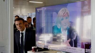 French President Emmanuel Macron visits France Inter's office, next to a TV screen displaying far-right presidential candidate Marine Le Pen. AFP