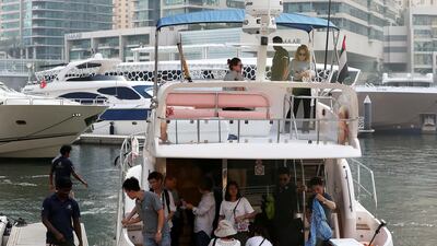Tourists, pictured in 2018, alight from a yacht after a tour of the marina. Pawan Singh / The National