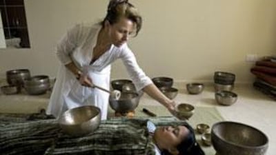 Zita Teimel holds a Tibetan 'singing bowl' during a therapy session. The bowls vary in size, producing different pitches over areas of the body.