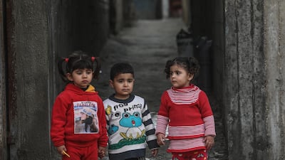 Palestinian children look on as their neighborhood is sprayed with disinfectant as a precaution against the spread of coronavirus, in the streets of the Al Nusairat refugee camp in the central Gaza Strip. EPA
