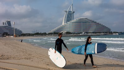 People prepare to surf on Jumeirah Beach in the wake of the first wave of Iranian attacks on the UAE. Getty