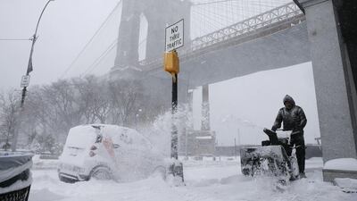 A man operates a snow blower near the Brooklyn Bridge in the borough of Brooklyn in New York on Saturday. Peter Morgan / AP