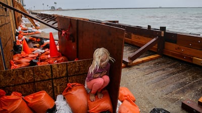 A girl takes shelter from sea spray as Post-Tropical Cyclone Rachel hits the coastline of Long Beach, California. Reuters