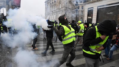 A demonstrator throws a tear gas canister during the demonstration of the yellow vests at the Arc de Triomphe. Getty Images
