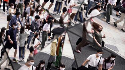 People wearing protective masks to help curb the spread of the coronavirus are reflected on the mirror wall of a shopping mall in Tokyo. AP