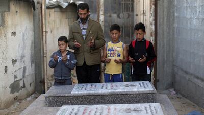 Father of a Palestinian victim of an Israeli military strike on a beach in Gaza visits with members of his family the graves of their loved-ones. Mahmud Hams / AFP PHOTO
