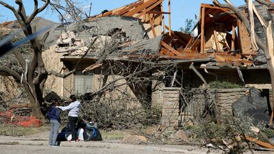 Women stand outside a house damaged by a tornado in the Preston Hollow section of Dallas. AP Photo