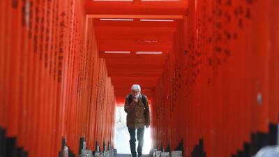 A man wearing face mask to protect against the spread of the coronavirus walks through a tunnel of torii gates at the Hie Shrine in Tokyo. AP Photo