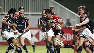 Japan's Takashi Kikutani, centre, runs with the ball past UAE players during their Asian Five Nations (A5N) rugby match last week. The lop-sided 93-3 loss for the UAE is a reminder the Emirtais need some assistance before they go from amateur to professional and find success at the international level. Karim Shahib / AFP