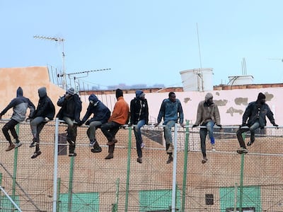 Migrants sit atop a border fence separating Morocco from the north African Spanish enclave of Melilla. AFP