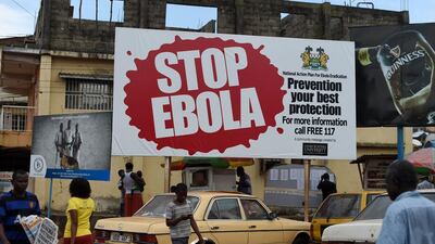 This picture from November 7, 2014 shows people walking past a billboard with a message about ebola in Freetown, Sierra Leone. Francisco Leong/AFP Photo