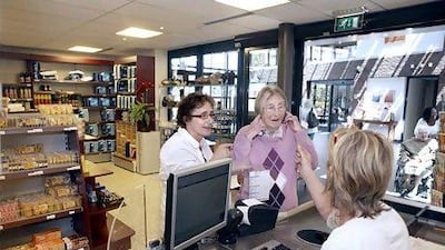 Mrs. Antje Roijter (right) and Petra van Eijk talk with cashier Trudy Vernooy at the store at the Hogewey residential complex.