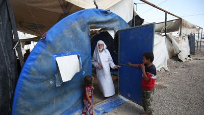 Displaced Iraqis stand at the entrance of a tent in a camp for internally displaced people near al-Khalidiyeh in Iraq's western Anbar province. While the election campaign is in full swing elsewhere in Iraq, the country's displaced camps barely register on the radars of those running for office, despite housing hundreds of thousands of people. Ahmad Al Rubaye / AFP