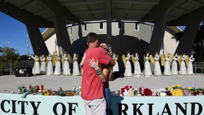 Zack King, left, comforts friend Mychal Bradley in front of 17 angels representing those who died in Wednesday's shooting at Marjory Stoneman Douglas High School. Taimy Alvarez / South Florida Sun-Sentinel via AP