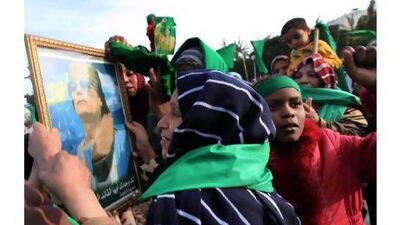Libyans supporting leader Muammar Qaddafi hold his portrait in the city of Zawiya, west of Tripoli. One reader urges Arab intervention in the conflict while another explains regional support for Qaddafi. Stringer/EPA