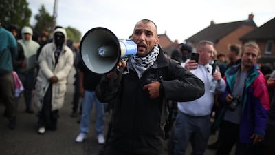 A man with a bullhorn and keffiyeh joins other residents outside the Merseyside Refugee Centre in Liverpool. Getty Images