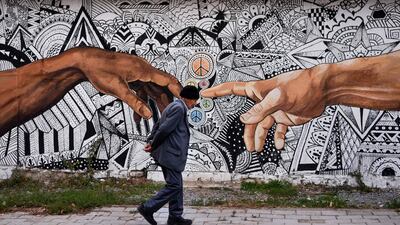 A pedestrian walks past a mural painted on the wall of a house in the town of Ferizaj, Kosovo. AFP