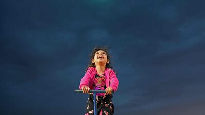 A girl smiles at an amusement park near a camp for displaced people in Afrin, on Syria's border with Turkey, during Eid Al Fitr.
