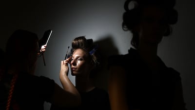 Hair is styled and make-up applied before models present creations by designer Mark Fast on day one of London Fashion Week. AFP