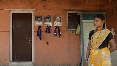 An Indian residents stands outside a house where flower-garlanded portraits of a murdered family are seen on a wall in Javkheda village in Ahmednagar district of India's Maharashtra state on November 25, 2014. Punit Paranipe/AFP Photo