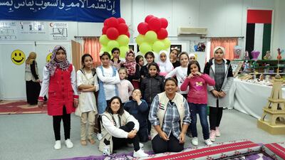 Syrian photographer Lana Albeik, sitting left, and spoken-word artist Afra Atiq, kneeling right, with children at the camp. Photo: MKS Jewellery