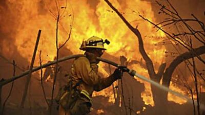 A fireman tries to save a home from being destroyed during a wildfire in Chatsworth, California.