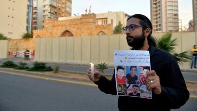 A Lebanese activist carries a candle and a picture for an Iraqi child who died during the uprising in Iraq during a gathering to support the children in the uprising in Iraq in front of the Iraqi embassy in Beirut. EPA