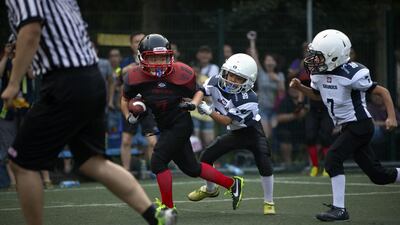 A young American football player dodges tacklers last month during a game in Beijing. Mark Schiefelbein / AP