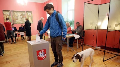 A voter with a dog casts his ballot during the first round of Lithuania's presidential election. AFP