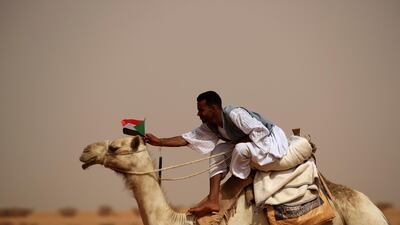 A supporter of Lieutenant General Mohamed Hamdan Dagalo, deputy head of the military council and head of paramilitary Rapid Support Forces (RSF), attaches a Sudanese national flag to the head of his camel during a meeting in Aprag village. Reuters