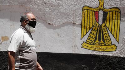A man wearing a protective face mask walks next to a wall painted with the colours of Egypt's flag. The country's latest funding comes on top of the $2.8bn the International Monetary Fund board approved last month to help it cope with the fallout from the Covid-19 pandemic. Reuters