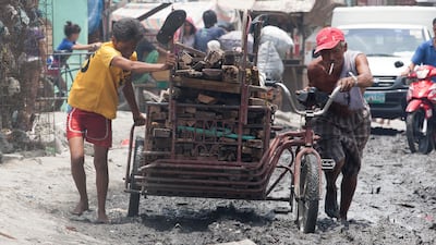 Scavengers push an overloaded kart through the muddy road way of squatters village at Smokey Mountain Reclamation area. Mike Young for the National