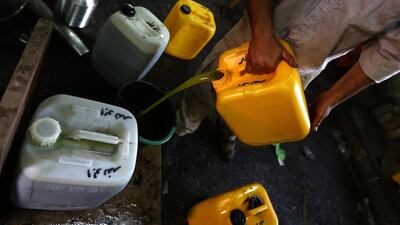 A worker fills freshly pressed olive oil into a container at a traditional stone press.
