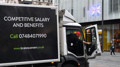 A worker delivers goods from a lorry advertising driving and warehouse vacancies in Leicester Square, London. Vacancies have increased in the UK amid a chronic labour shortage. AFP