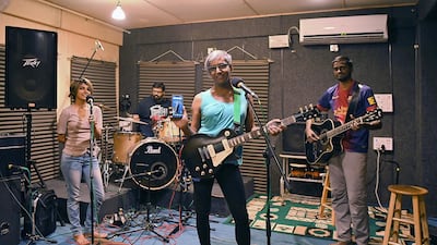 Sangeeta Agnes Hosea, centre, lead singer and musician of the Indian band Midnight Poppies, poses for a photograph with her smartphone during a jam session in Bangalore. Sangeeta uses her smartphone to record her songs and also to promote the band on social media. AFP