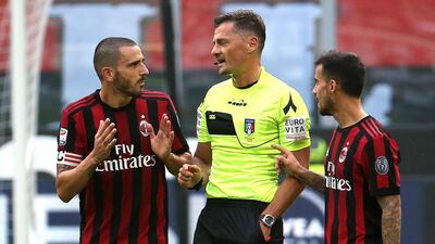 AC Milan defender Leonardo Bonucci, left, speaks with referee Piero Giacomelli, centre, after receiving a red card against Genoa. Matteo Bazzi / AP Photo