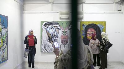 Guests visit with one another and take pictures of artwork by Philippine artist Janos De La Cruz during the opening for the Philippine Art Month.