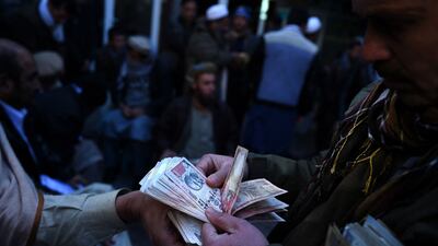 Afghan money changers count banknotes at the currency exchange Sarayee Shahzada market in Kabul. AFP