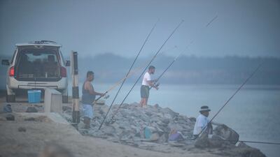 Anglers patiently wait for a catch at the Yas Island Iron Bridge area on a foggy morning.
