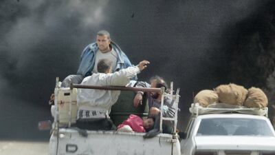Iraqis fleeing Baghdad sit with their belongings in the back of a pick-up truck on March 31, 2003, as smoke billowing from burning oil trenches covers the sky. AFP