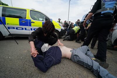 A pro-Palestine campaigner lies on the road during a protest outside the Thales factory in Govan. PA