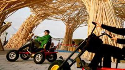 Two boys ride past a domed wooden sculpture comprising seven pillars at the Corniche in Abu Dhabi yesterday.