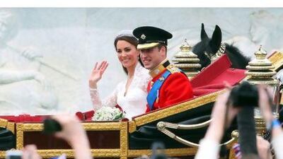 Britain's Prince William and his wife Kate, Duchess of Cambridge, wave as they travel in the 1902 State Landau carriage along the Processional Route to Buckingham Palace.