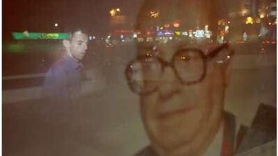 A photograph of Fouad Zakariyya is reflected in a window of the Sultan Bin Ali Al Owais Cultural Foundation in Dubai.