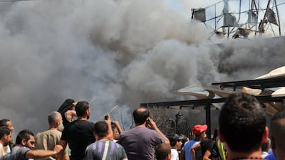 Smoke rises above people gathering near al-taqwa mosque on the site of a powerful explosion in the northern Lebanese city of Tripoli on August 23, 2013. Two powerful explosions killed several people: one rocked the city centre near a mosque and the home of outgoing Prime Minister Najib Mikati, the second one struck near the port of the restive city with a Sunni Muslim majority. The explosions come a week after a suicide car bombing killed 27 people in a Beirut stronghold of the Lebanese Shiite movement Hezbollah, which is fighting alongside Assad's forces. AFP PHOTO IBRAHIM CHALHOUB *** Local Caption *** 789757-01-08.jpg