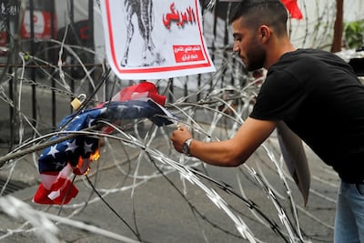 A protester burns a representation of an American flag during a protest against US interference in Lebanon's affairs, near the US embassy in Awkar, northeast of Beirut, on July 10. AP