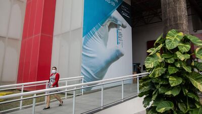 A worker in Rio de Janeiro passes in front of a sign at a Fiocruz production facility that reads in Portuguese: "We produce the Covid-19 vaccine here." Brazil has administered 64 million Covid vaccine doses, with an average rate estimated at 659,189 doses per day. Bloomberg